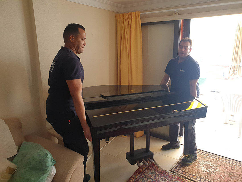 operario de mudanzas en canarias realizando transporte de piano en contenedor